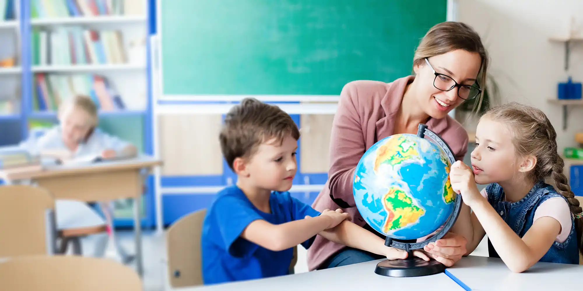 A teacher showing two children where countries are on a globe